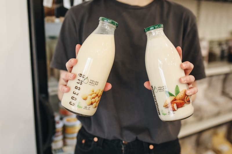 Persona sosteniendo dos botellas de leche de almendras.