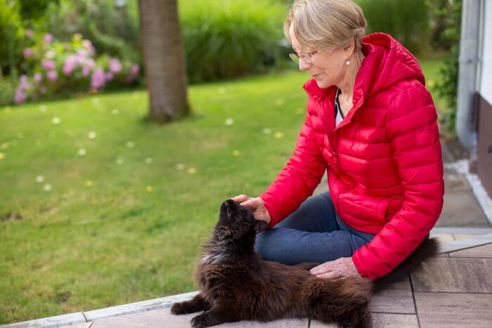 Una persona que busca al aire libre con expresión preocupada, probablemente buscando un gato perdido.