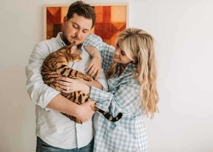 Encantadora imagen que muestra a una linda pareja compartiendo un momento encantador con su gato, retratando la alegría y el amor que las mascotas pueden aportar a las relaciones.