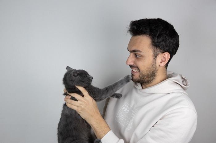 Una imagen que representa a un hombre interactuando con un gato.