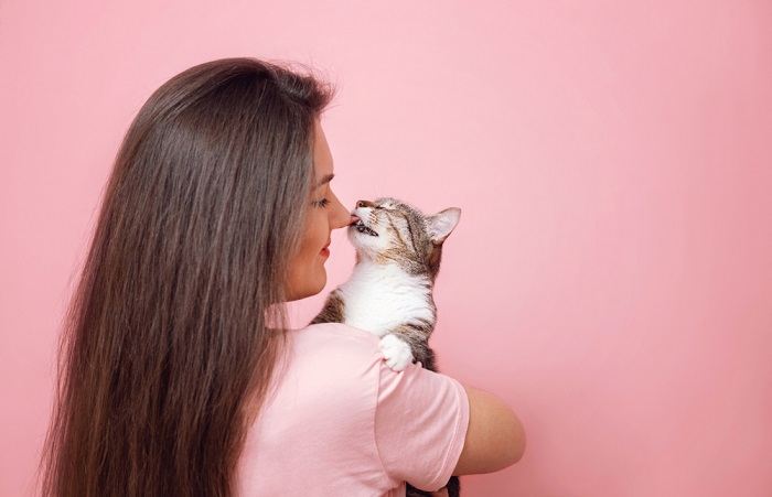 Imagen que captura una dulce interacción cuando un gato curioso lame tiernamente la mano de una niña encantada, resaltando el vínculo entre ellos.