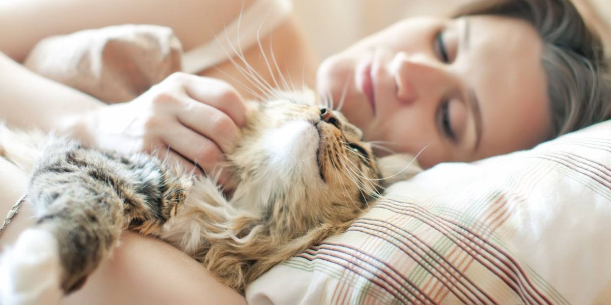 Mujer durmiendo con gato en la cama