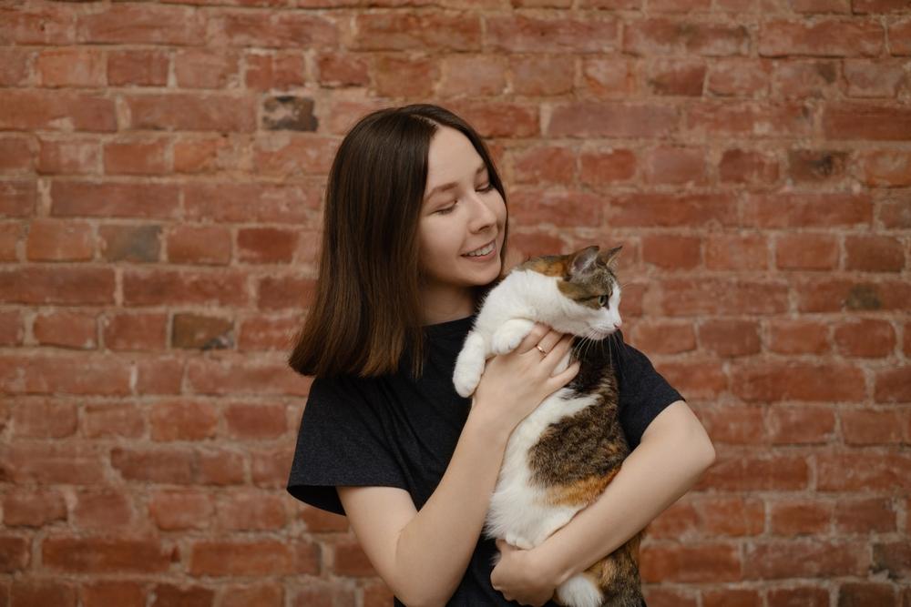 Mujer sosteniendo un gato y mirando hacia otro lado