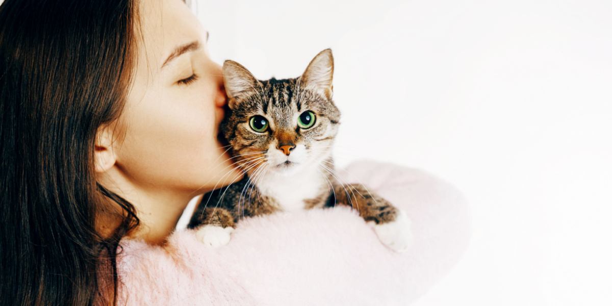 Mujer besa y abraza a un gato