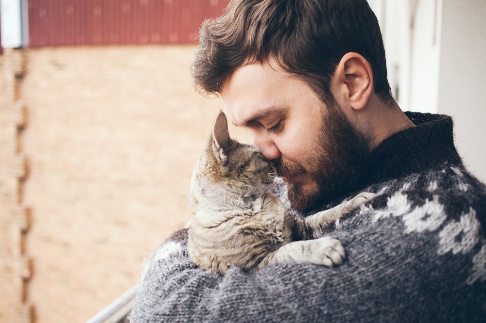 Retrato de gato feliz con ojos cerrados y hombre joven.